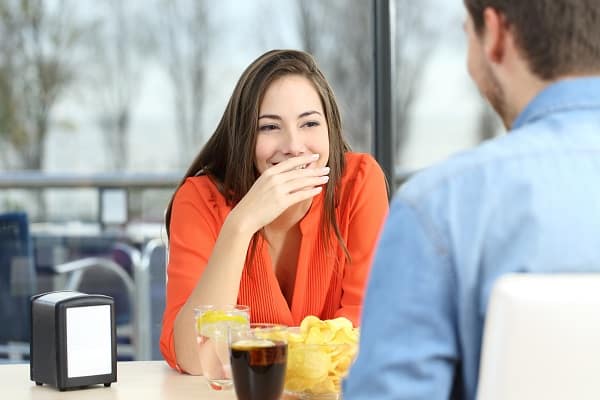 Woman covering her smile because she's embarrassed about yellow teeth