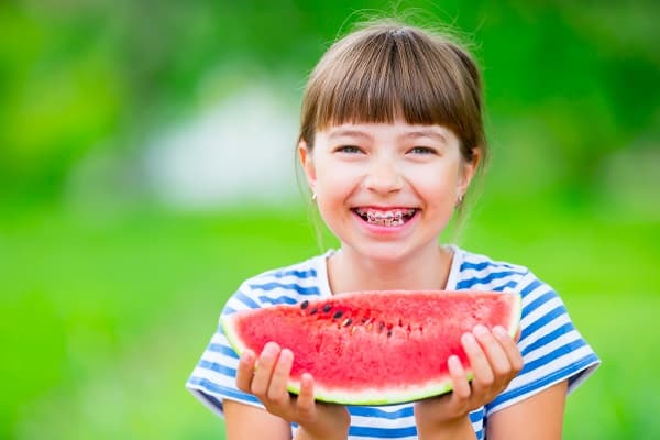Young girl in Stapleton CO wearing braces and eating watermelon