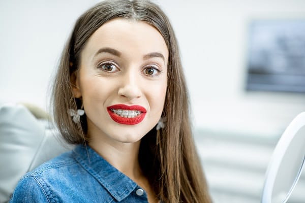 Woman smiling after having adult braces placed at the orthodontist's office