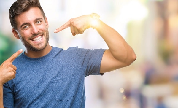 Man pointing to his smile to show off adult braces results