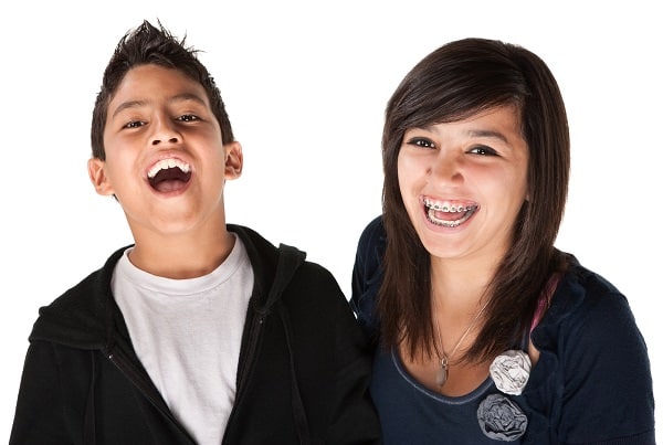 Brother and sister smiling wide with one sibling having braces