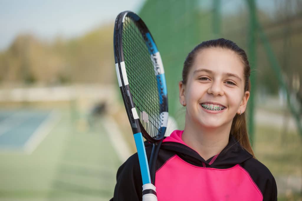 Young Girl With Braces Posing Holding A Tennis Racket