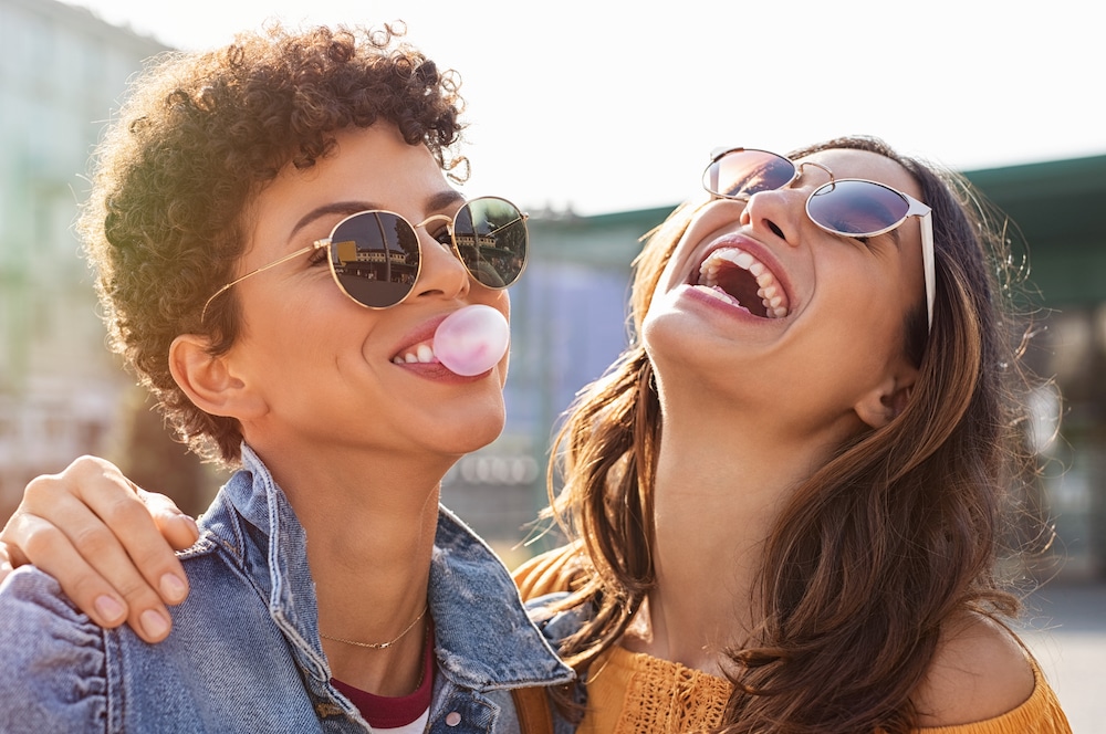 Woman laughing while friend blows a gum bublble