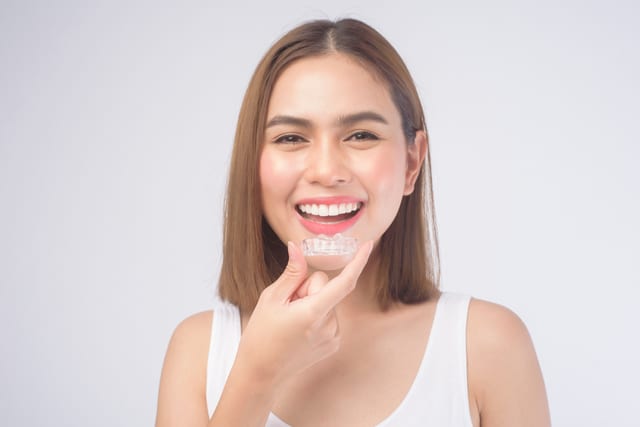 smiling woman holding invisalign braces