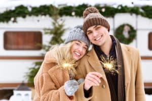 Romantic Couple In Knitted Hats Posing With Sparklers At Winter Camping