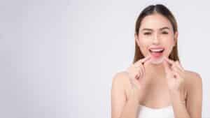 Young,Smiling,Woman,Holding,Invisalign,Braces,In,Studio,,Dental,Healthcare