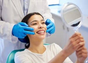 A woman looking in the mirror after straightening her teeth with clear aligners