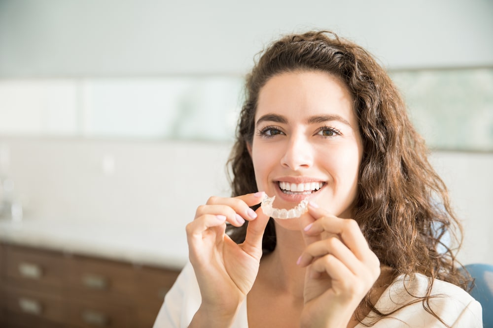 A woman holding a clear retainer in Denver, CO