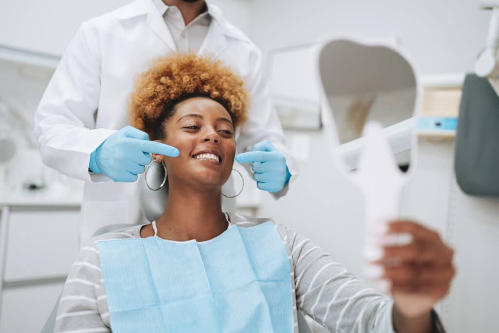 Orthodontist examining a smiling patient’s teeth during a bite and alignment consultation.