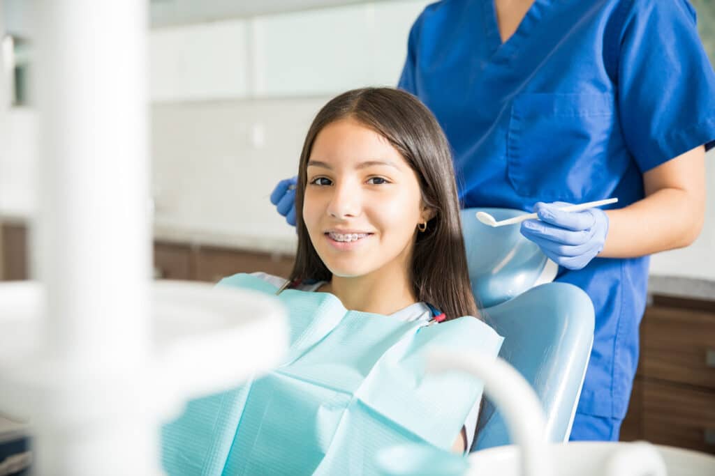 Teen patient with braces smiling during an orthodontic appointment with a dental professional.
